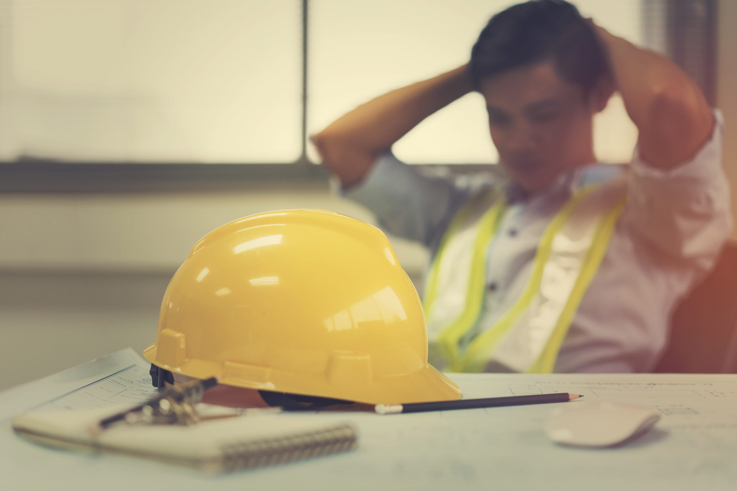 Male construction worker with hands on head showing that he is under stres and may need mental health and suicide prevention training.
